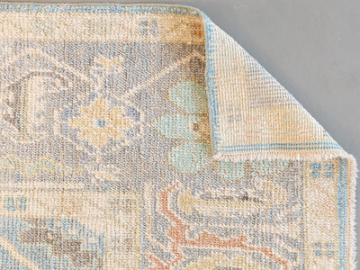 Corner folded back on a extra large blue & green Turkish Oushak rug.