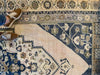 Corner of a extra large blue and green Sivas Turkish rug with a woman's feet.