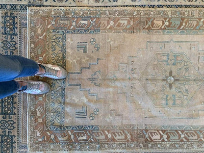 Top down shot of a medium brown and grey Sivas Turkish rug with woman's feet.