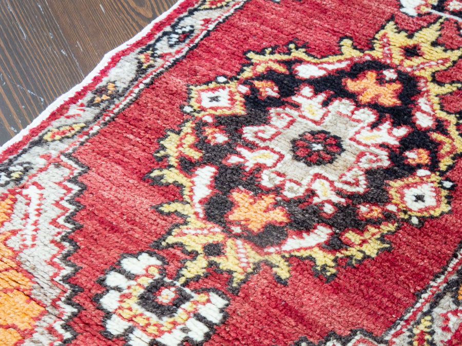 Central medallion on a red & orange extra small Turkish Yastik Rug.