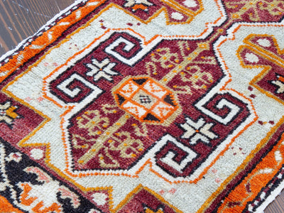 Central medallion on a red & orange extra small Turkish Yastik Rug.