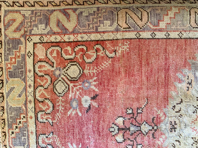 Close up of corner and border knot work on a medium red & orange Guney Turkish rug.