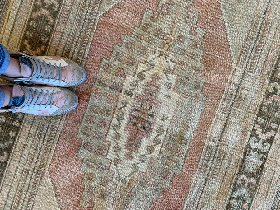 Woman standing on a red & orange medium Sivas Turkish Rug.