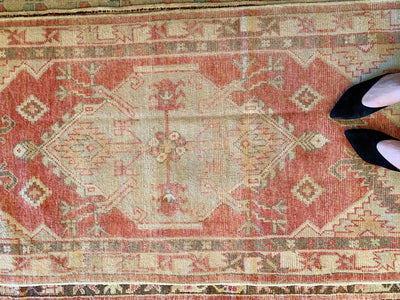 Woman in black heels on a small red & orange Cal Turkish rug.