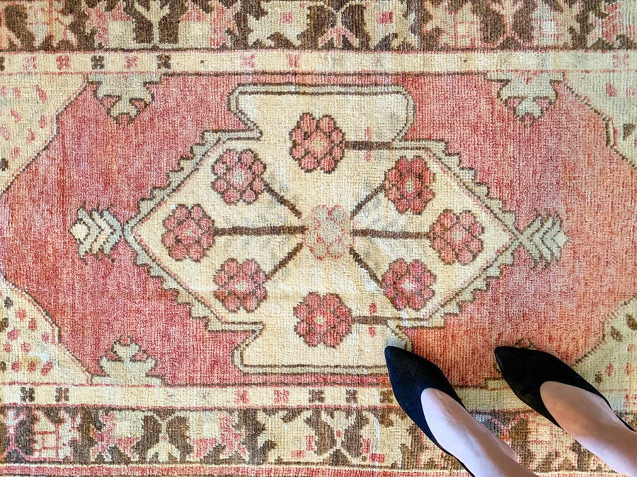 Woman standing on a small red & orange Cal Turkish rug.