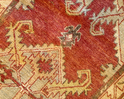 Close up of hand knotting on a small red & orange Cal Turkish rug.