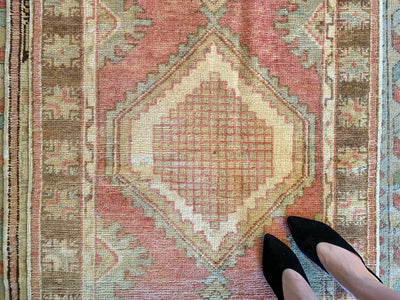Woman in black heels on a small red & orange Cal Turkish rug.