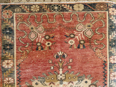 Close up of corner work on a hand knotted small red & orange Guney Turkish rug.