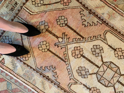 Woman in black heels on a small red & orange Turkish rug.