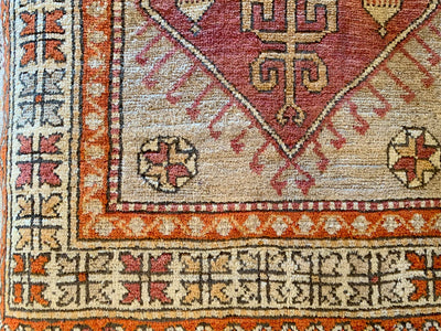 Close up of hand knotting on the corner of a small red & orange Yuntdag Turkish rug.