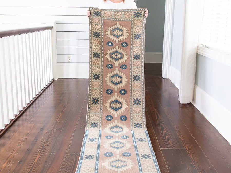 Woman holding red & orange varosha Turkish rug runner.