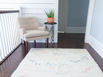 Chair on an upstairs landing with a white medium Turkish Tulu rug.